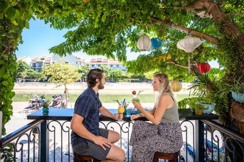 a man and woman sitting at a table on a balcony at Lantana Boutique Hoi An Hotel in Hoi An
