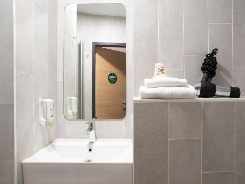 een badkamer met een wastafel en een spiegel bij B&B Hotel Schwerin-Süd in Schwerin