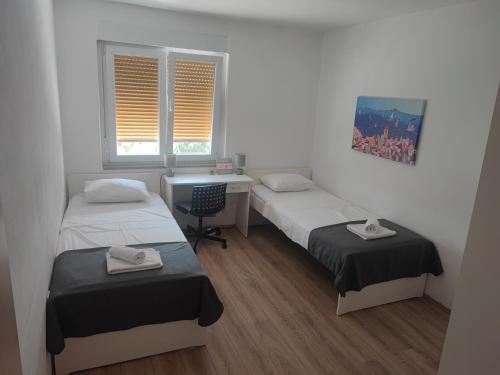 Habitación con 2 camas, escritorio y 2 ventanas. en Apartment Magic View, en Rijeka
