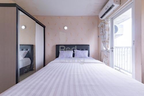 a large white bed in a room with a window at RedLiving Apartemen Grand Sentraland - Dragon Apartel Tower Pink in Karawang