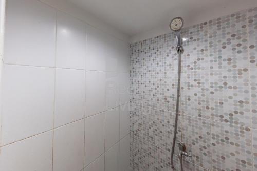La salle de bains est pourvue d'une douche et d'une horloge murale. dans l'établissement RedLiving Apartemen Grand Sentraland - Dragon Apartel Tower Pink, à Karawang