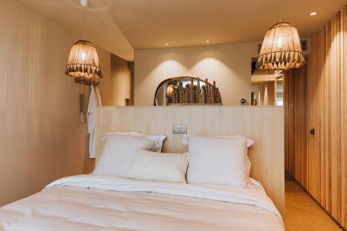um quarto com uma cama com lençóis brancos e duas luzes em BONK suites em Middelkerke