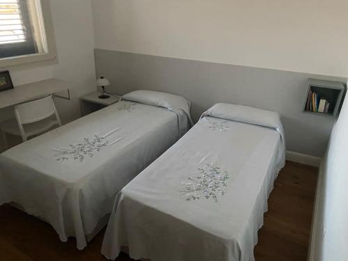 2 Betten in einem kleinen Zimmer mit weißer Bettwäsche in der Unterkunft Casa Vacanze Zia Meme in San Donato di Lecce