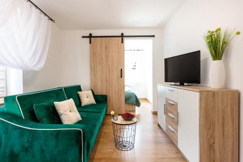 a living room with a green couch and a television at Green House Ełk in Ełk