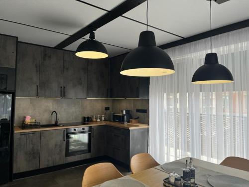 uma cozinha com duas luzes e uma mesa com cadeiras em Belweder LOFT em Nysa