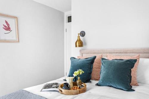 a tray of food on a bed with blue pillows at Harbourside 3 - Luxury Riverside Apartment in Dartmouth