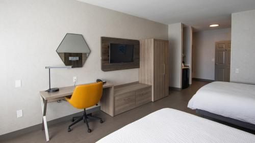 a bedroom with a desk and a bed and a yellow chair at Holiday Inn Express Oakdale, an IHG Hotel in Oakdale
