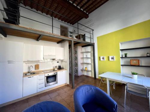 a kitchen with white cabinets and a table and blue chairs at Loft storico in pieno centro! in Livorno