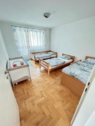 um quarto com 3 camas e um piso de madeira em Doboj Apartman em Doboj