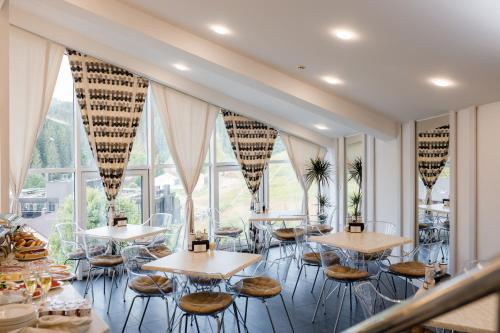 a restaurant with tables and chairs and large windows at Chevalier Hotel & SPA in Bukovel