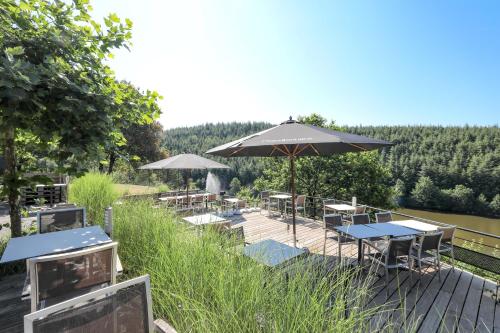 a deck with tables and umbrellas in the grass at Hotel Bô Rivage in Neufchâteau
