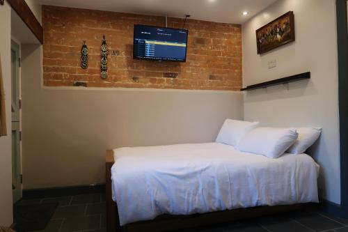 a bedroom with a white bed with a tv on the wall at The Old Pantry at Hill Farm in Penley