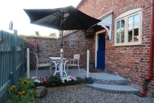 a patio with an umbrella and a table and chairs at The Old Pantry at Hill Farm in Penley