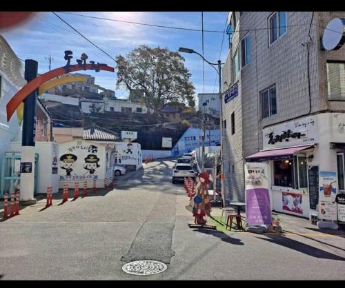 Un gruppo di persone in piedi in una strada di città di Dongpirang Purple House 2 a Tongyeong