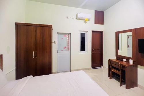 a bedroom with a bed and a desk and a television at Teratai Residence Mitra RedDoorz in Medan