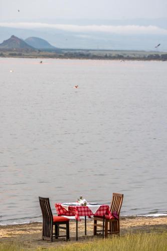 a table with two chairs next to the water at Sentrim Elementaita Lodge in Elmenteita