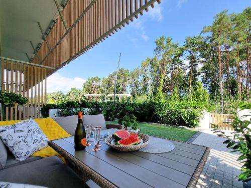 a table with a bowl of fruit and a bottle of wine at visit baltic - Apartament Plażowy Casa in Świnoujście