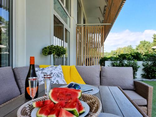 uma mesa com uma garrafa de vinho e um prato de melancia em visit baltic - Apartament Plażowy Casa em Świnoujście