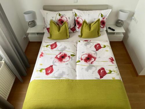 een bed met groene kussens en roze bloemen erop bij Ferienzimmer Olli Koch in Reken