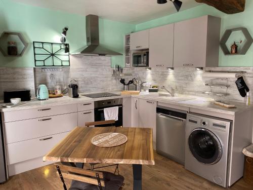 a kitchen with white cabinets and a wooden table at Maisonnette au cœur du village in Le Bar-sur-Loup