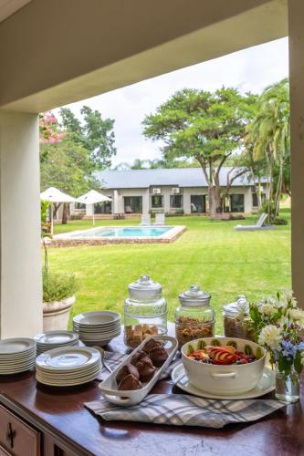 a table with plates and bowls of food on it at Hamiltons Lodge & Restaurant in Malelane