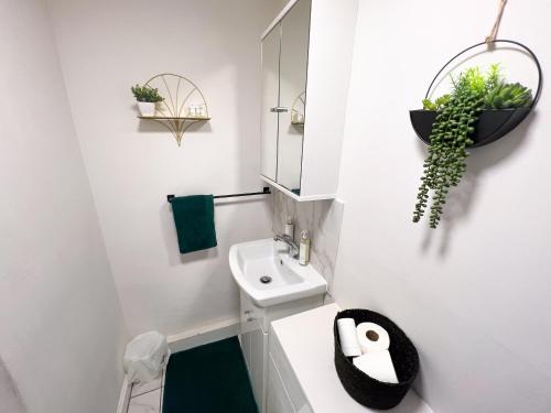 Baño blanco con lavabo y espejo en Central Canterbury Apartment with Parking, en Kent