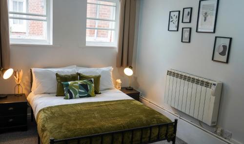 1 dormitorio con 1 cama con sábanas y almohadas verdes en Central Canterbury Apartment with Parking en Kent