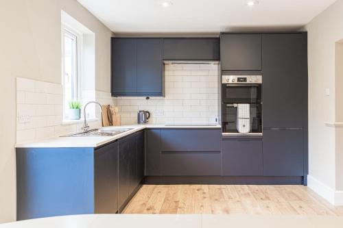 a kitchen with black cabinets and a blue counter top at Comfortable 5-Bedroom House in Cheltenham in Cheltenham