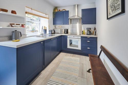 a kitchen with blue cabinets and white counter tops at Host & Stay - Stone Row in Skinningrove
