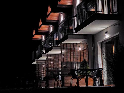a table and chairs in front of a building at night at Bieszczadzkie Siedlisko in Polańczyk