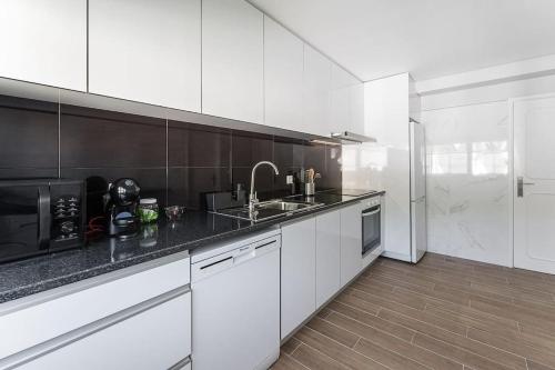 a white kitchen with a sink and a microwave at Fernandes Apartments in Ponte de Lima
