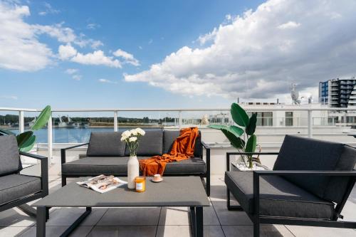 a balcony with chairs and tables and a view of the water at Sol Marina Resort Wyspa Sobieszewska I - LoftAffair Collection in Wiślinka