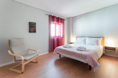 um quarto com uma cama, uma cadeira e uma janela em Fernandes Apartments em Ponte de Lima