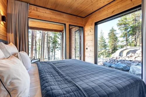 um quarto com uma cama grande e janelas grandes em Saunamäki L - Exquisite Luxurious Seafront Villa em Salo