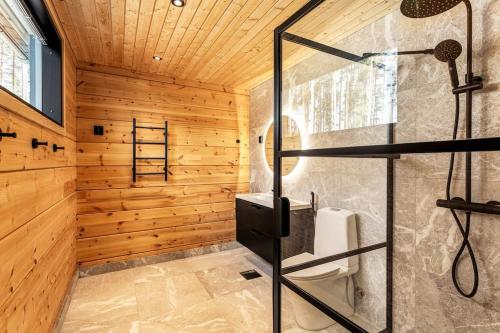 a bathroom with a shower with wooden walls at Saunamäki L - Exquisite Luxurious Seafront Villa in Salo