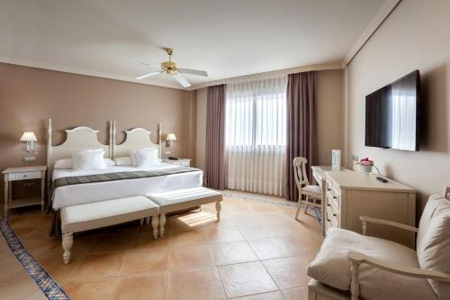 a bedroom with a bed and a desk and a couch at Barceló Marbella in Marbella