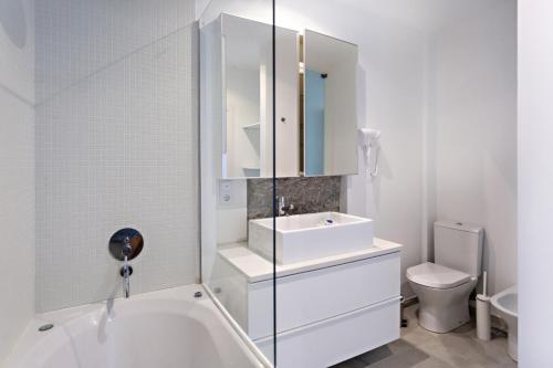 La salle de bains blanche est pourvue d'un lavabo et de toilettes. dans l'établissement Tavira Historical Center Apartments, à Tavira