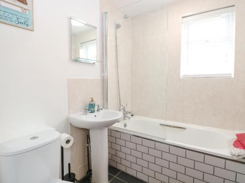 a bathroom with a sink and a toilet and a bath tub at Seashell Cottage in Lowestoft