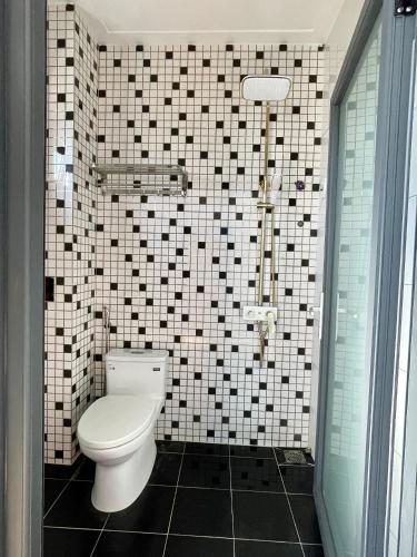 a bathroom with a toilet and a tiled wall at TRANG Homestay in Bao Loc