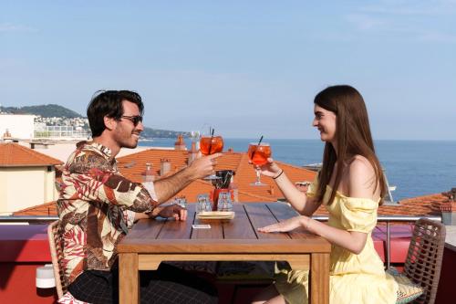 a man and woman sitting at a table with drinks at AC Hotel by Marriott Nice in Nice