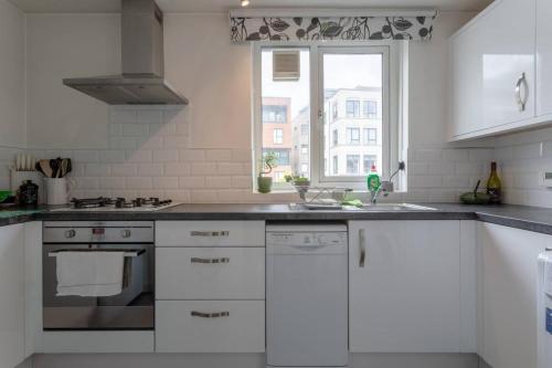 a kitchen with white cabinets and a sink and a window at Stylish 1 Bedroom Apartment Near Clapham Junction in London