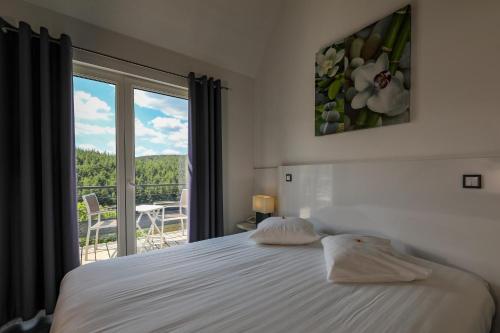 een slaapkamer met een bed en een raam met uitzicht bij Hotel Bô Rivage -- Eden-Ardenne in Neufchâteau