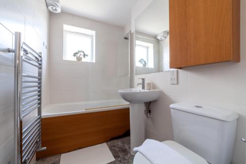 a white bathroom with a toilet and a sink at The South Wimbledon Collection in London