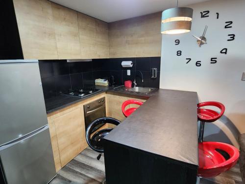cocina con encimera y 2 taburetes rojos en Nui 2 apartamento, en Punta Arenas