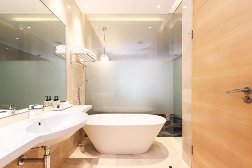a bathroom with a white tub and a sink at Vineyard Hotel in Cape Town