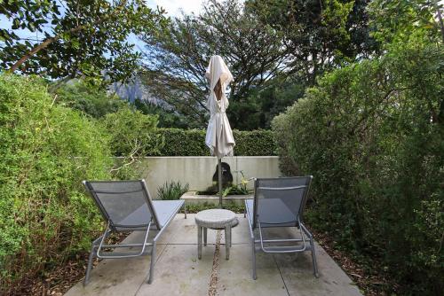 a patio with two chairs and a table with an umbrella at Vineyard Hotel in Cape Town