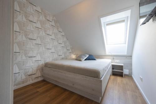 a bedroom with a bed and a wall with a window at LA 4a - Ferienreihenhaus in Schottwarden