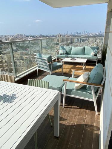 a balcony with chairs and couches on a building at Deluxe & Terrace with City Overview by FeelHome in H̱olon