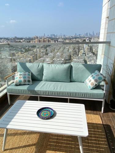 a couch on a balcony with a view of a city at Deluxe & Terrace with City Overview by FeelHome in H̱olon