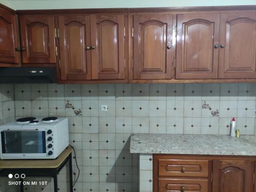 a kitchen with wooden cabinets and a white microwave at Vicky's House in Kymi